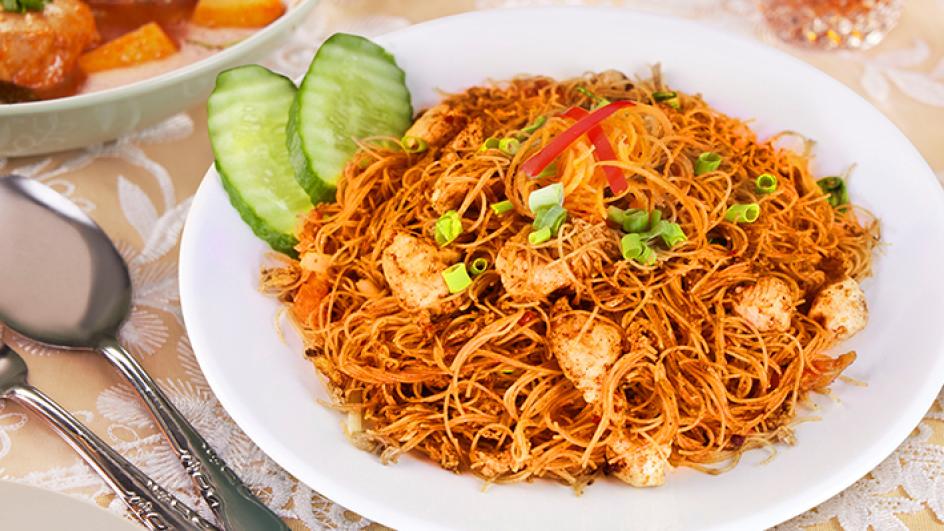 Sepiring bihun goreng dengan sayuran segar dan irisan telur, disajikan hangat dengan bumbu gurih yang khas